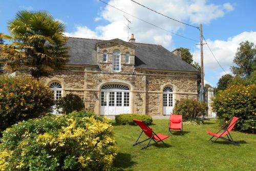 two red chairs in front of a stone house at l'orangerie in Pontivy