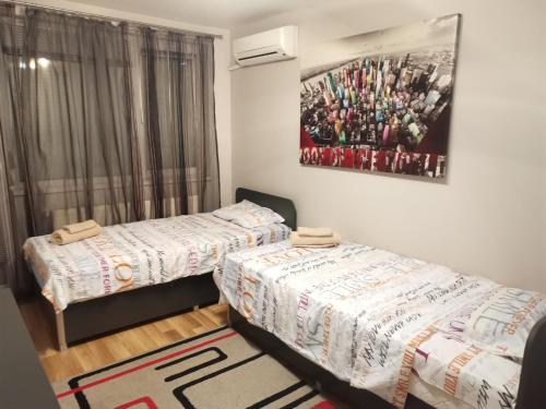 a bedroom with two beds and a picture on the wall at Уютен апартамент в централната част на Стара Загора in Stara Zagora