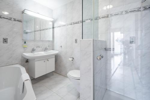 a white bathroom with a toilet and a shower at Casa Mundaun in Falera