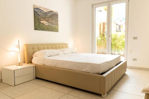 a white bedroom with a large bed and a window at Yachting Residence in Lavena Ponte Tresa