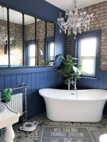 a bathroom with a white tub and a blue wall at Lyndhurst - Victorian villa with heated pool in Roby