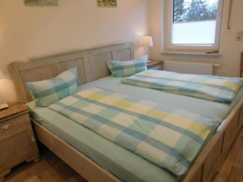 uma cama com lençóis de xadrez azuis e amarelos e uma janela em Ferienhof Westermann Waldblick em Lähden