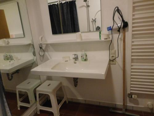 a bathroom with a sink and a mirror and two stools at Ferienhof Westermann Waldblick in Lähden