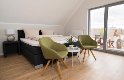 een slaapkamer met een bed en 2 stoelen en een tafel bij Ostsee - Appartement Nr 96 "Seehase" im Strand Resort in Heiligenhafen