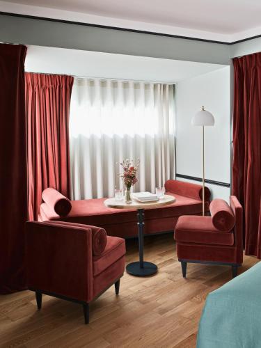 a living room with red furniture and a table and chairs at Hôtel Botaniste in Paris