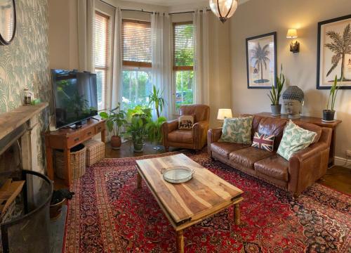Lyndhurst - Victorian villa with heated pool في Roby: غرفة معيشة مع أريكة وطاولة قهوة