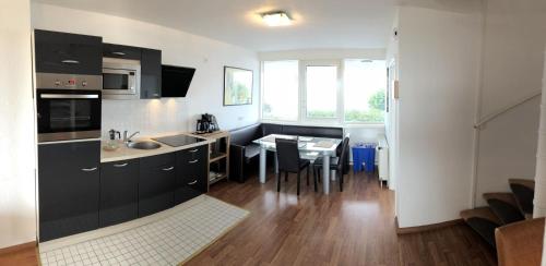 une cuisine avec des armoires noires et une salle à manger dans l'établissement Apartment 45, à Wilhelmshaven