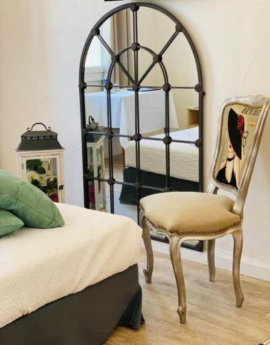 a bedroom with a bed and a chair and a mirror at Hôtel Restaurant La Plage in Saint-Louis-du-Rhône