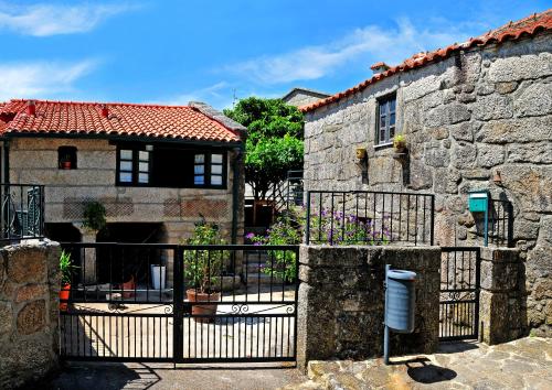 a stone house with a black gate in front of it at Casinha da Horta com Jacuzzi in Soajo