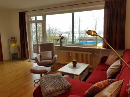 - un salon avec un canapé et des chaises rouges ainsi qu'une grande fenêtre dans l'établissement Stadtdomizil am Binnensee, à Heiligenhafen