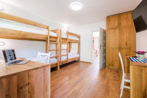 a room with two bunk beds and a desk with a laptop at Villa Kliwer 50 metrów od morza in Rowy