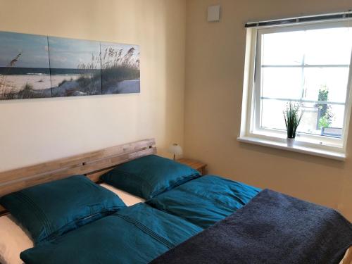 ein Schlafzimmer mit einem Bett mit blauen Kissen und einem Fenster in der Unterkunft Ferienwohnung "Ostseeglück" in Grömitz