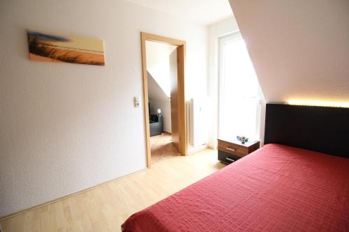 um quarto com uma cama com uma colcha vermelha em Strandperle App 10 em Dierhagen