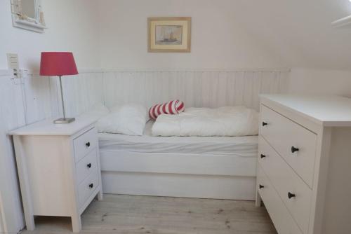 una camera bianca con un letto con una lampada e un comò di FöhrTraum a Oldsum