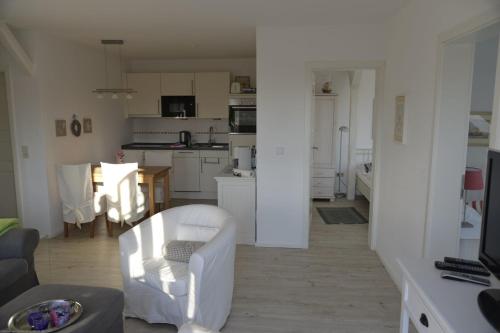 een woonkamer en een keuken met witte kasten bij FöhrTraum in Oldsum