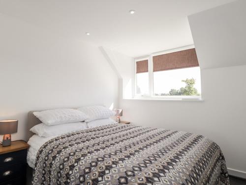 a white bedroom with a bed and a window at Clyne Cottage in Elgin