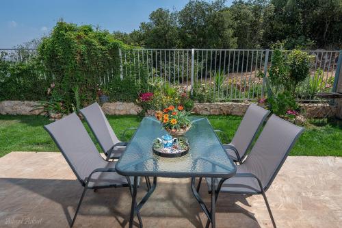 a table with two chairs and a bowl of flowers on it at בית גלילי מול היער in ‘Ein Ya‘aqov