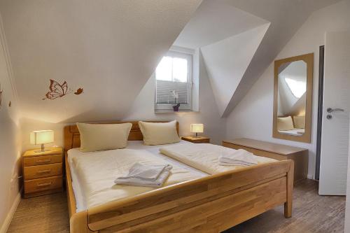 ツィングストにあるAm Deich 37 Sandkornのベッドルーム1室(白いシーツと鏡付きのベッド1台付)