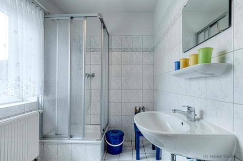 a white bathroom with a sink and a shower at Bossow, Regina in Zingst