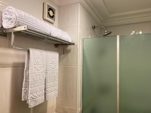 a bathroom with a glass shower door and towels at Itatiaia Hotel Passo Fundo in Passo Fundo