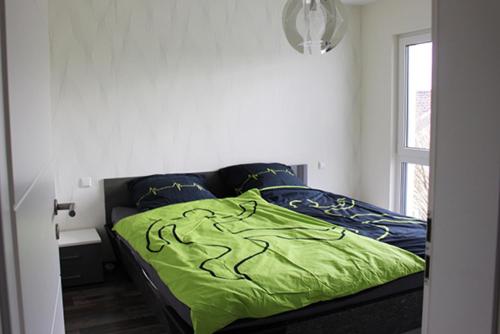 a bed with a green comforter in a bedroom at Ferienhaus ALB-QUELLE in Gomadingen