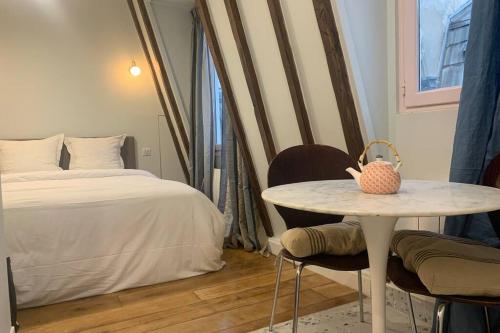 une chambre avec un lit et une table et un lit dans l'établissement PARIS 4 LE MARAIS Hôtel de Ville LIFT, à Paris