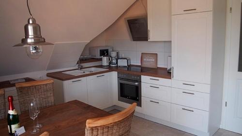 a kitchen with white cabinets and a wooden table at Jolle in Zingst