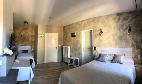 - une chambre avec 2 lits, une table et une porte dans l'établissement Logis Hôtel Restaurant Métropole, à Mirande