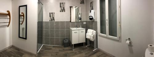 La salle de bains est pourvue d'un lavabo et d'un miroir. dans l'établissement Logis Hôtel Restaurant Métropole, à Mirande