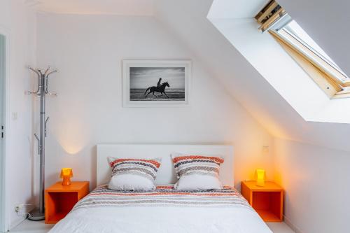 - une chambre blanche avec un lit et deux tables orange dans l'établissement Le Galop, à Tréméreuc