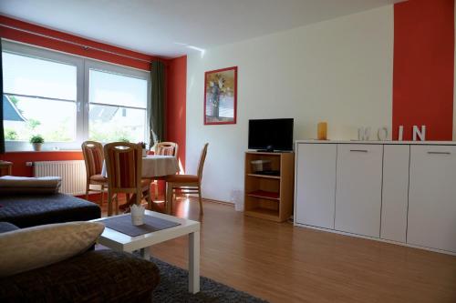 uma sala de estar com um sofá, uma mesa e uma televisão em Ferienwohnung Wattfischer em Cuxhaven