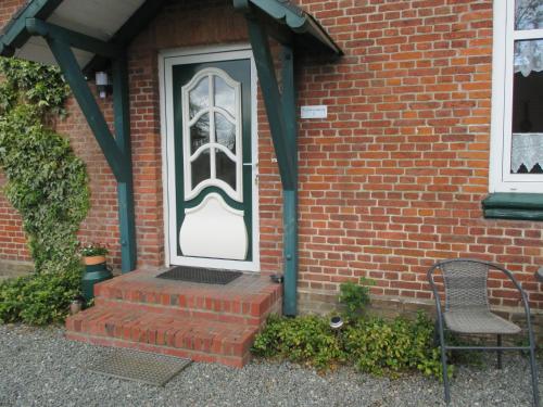a front door of a brick house with a chair at FeWo 2 - Haus Lorenzen in Hörsten