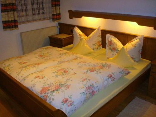 a bed with a floral comforter and four pillows at Mädelegabel in Ofterschwang