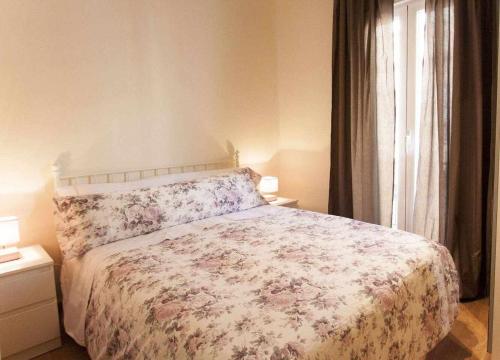 a bedroom with a bed with a floral bedspread and a window at Dos dormitorios al lado del metro centrico moderno in Madrid