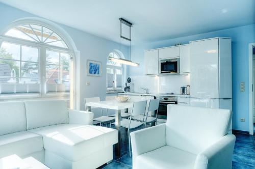 a kitchen and living room with white furniture and a table at Villa Obendtied, FW 4 in Zingst