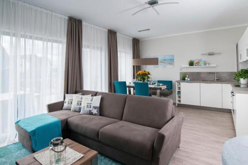 ハイリゲンハーフェンにあるOstsee - Appartement Nr 161 "Strandgut" im Strand Resortのリビングルーム(ブラウンソファ付)、キッチンが備わります。