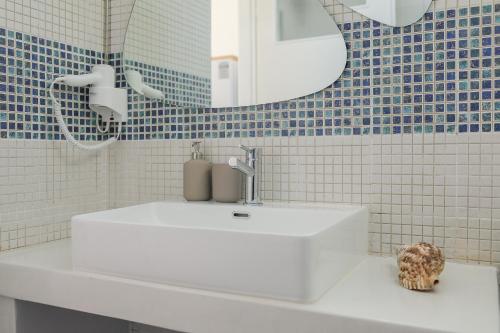 W łazience znajduje się biała umywalka i lustro. w obiekcie Petinos traditional house w mieście Thirasia
