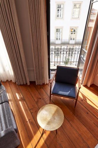 a living room with a chair and a table and a window at Rio da Vila in Porto