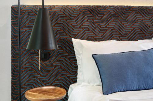 a bed with a blue pillow and a black lamp at Rio da Vila in Porto