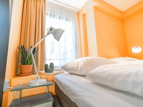 a bedroom with orange walls and a bed with a lamp at Pink Flamingo Boutique Hostel in The Hague