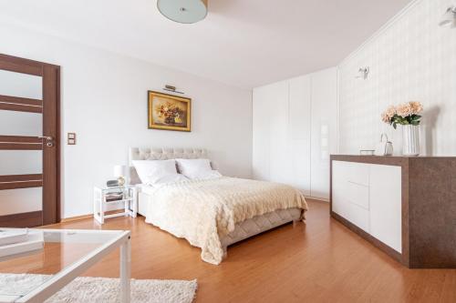 a white bedroom with a bed and a table at Prestige Apartament Przy Nosalu in Zakopane