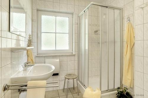 a white bathroom with a sink and a shower at Am Deich 44 in Zingst