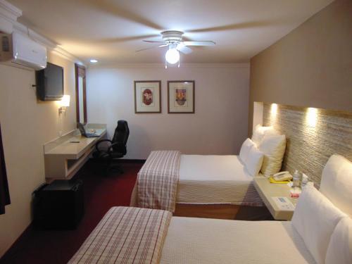 a hotel room with two beds and a desk at Hotel Royal Inn in Monclova