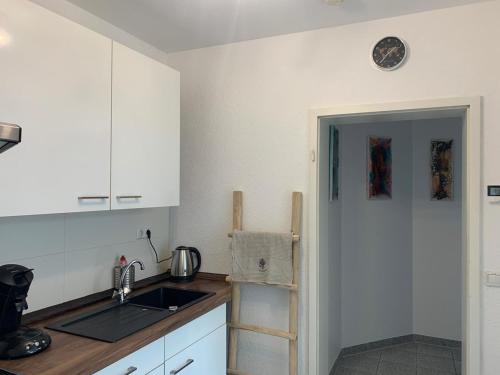 cocina con armarios blancos, fregadero y escalera en Ferienwohnung Ilmradweg, en Kranichfeld