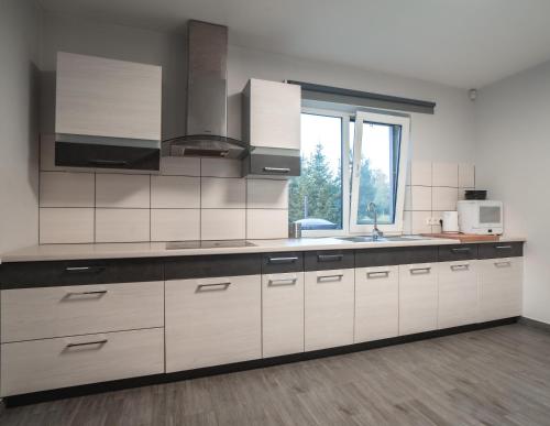 a kitchen with white cabinets and a sink and a window at Vėjo Malūnų sodyba - vila in Paserninkai