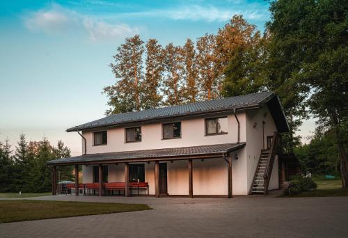 a large white house with a porch and a table at Vėjo Malūnų sodyba - vila in Paserninkai