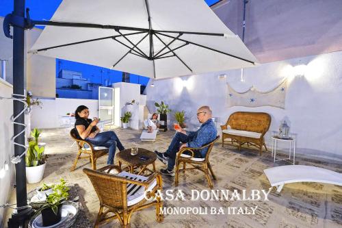 Un uomo e una donna seduti sotto un ombrellone di Casa Donnalby a Monopoli