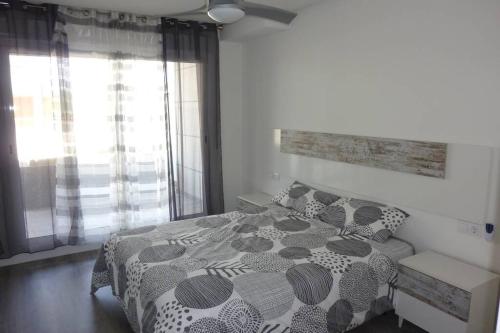 a bedroom with a bed with a black and white comforter at Brisa de Mar en Oliva Nova, junto a MET y golf in Oliva