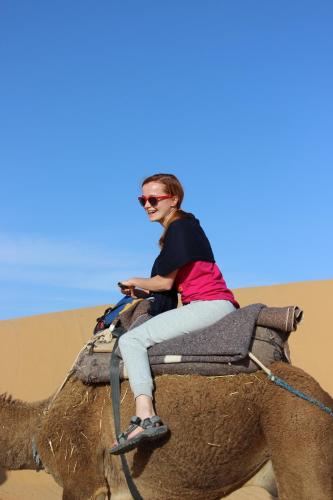 a woman riding on the back of an elephant in the desert at Maison d'Hôte Valentine in Tinerhir