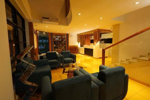 a living room with couches and chairs and a staircase at HOTEL LA SERENE Mattannur in Mattanūr